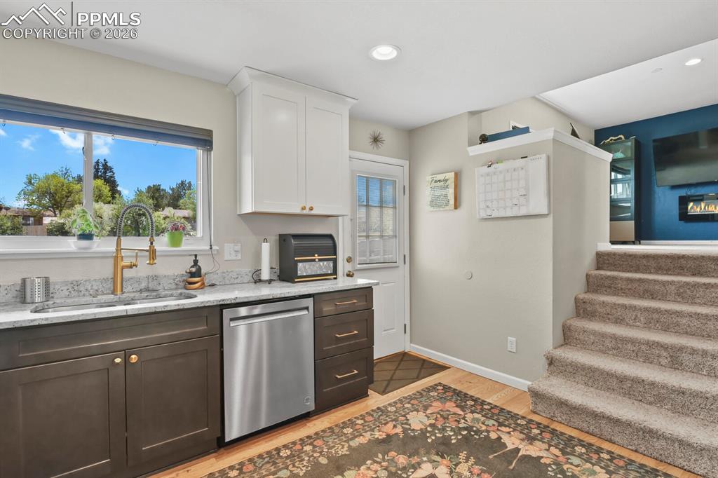 Image 8 of 38: Kitchen featuring granite countertops, a stainless steel sink with a gold f
