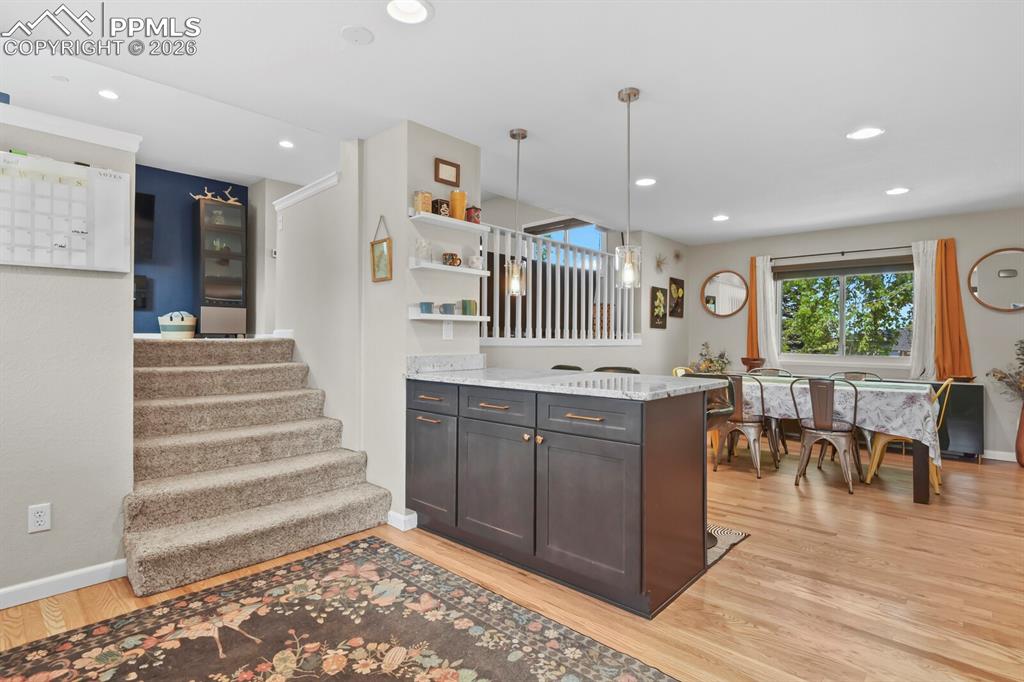 Image 9 of 38: The property features hardwood floors, a kitchen island with a granite coun