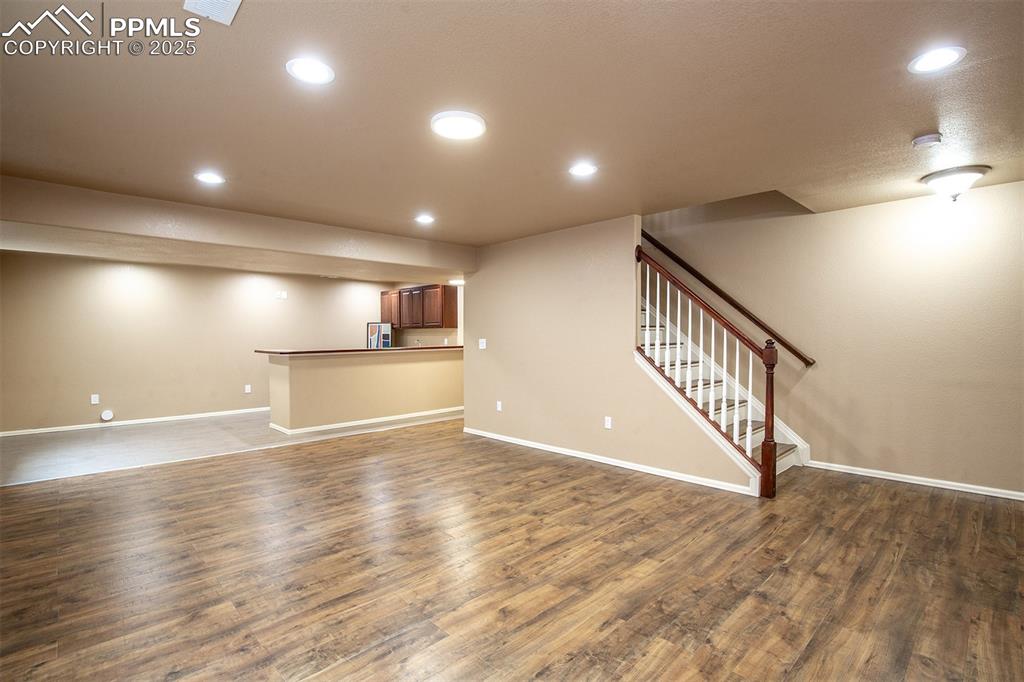 Image 13 of 46: Unfurnished living room with dark wood-style flooring, stairs, and recessed