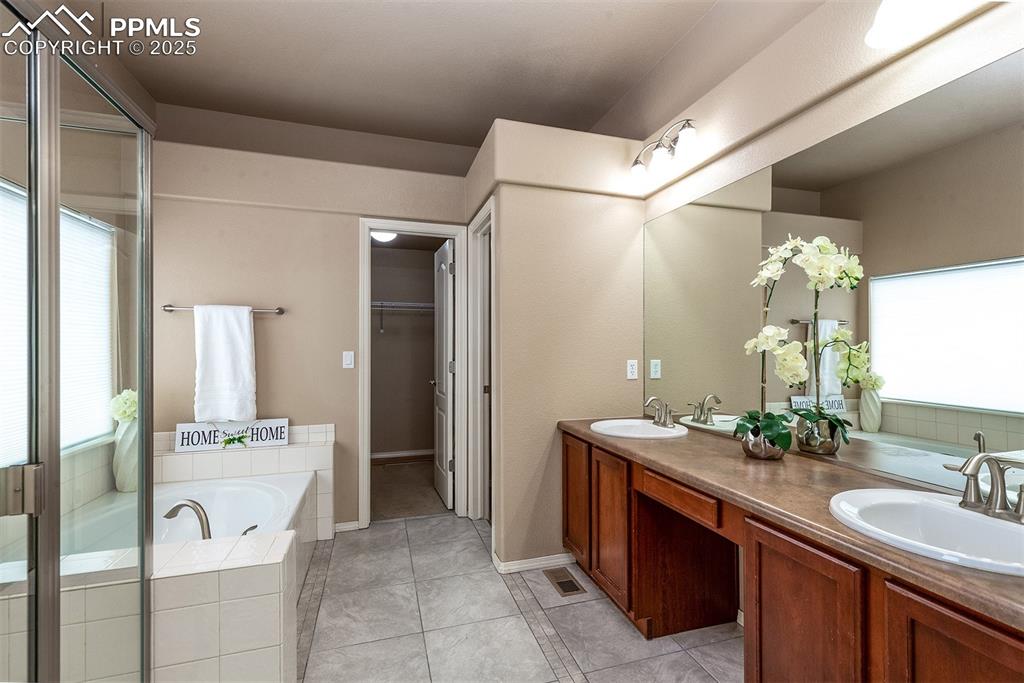 Image 19 of 46: Bathroom with double vanity, a garden tub, tile patterned floors, and a wal