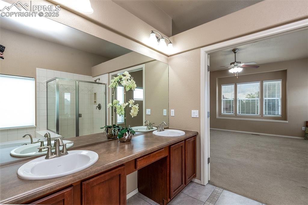 Image 20 of 46: Full bath featuring a shower stall, double vanity, a ceiling fan, and tile 