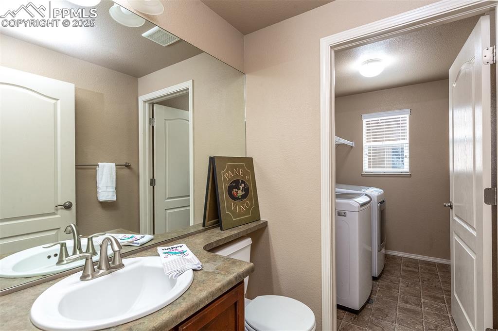 Image 31 of 46: Bathroom with washing machine and clothes dryer and vanity