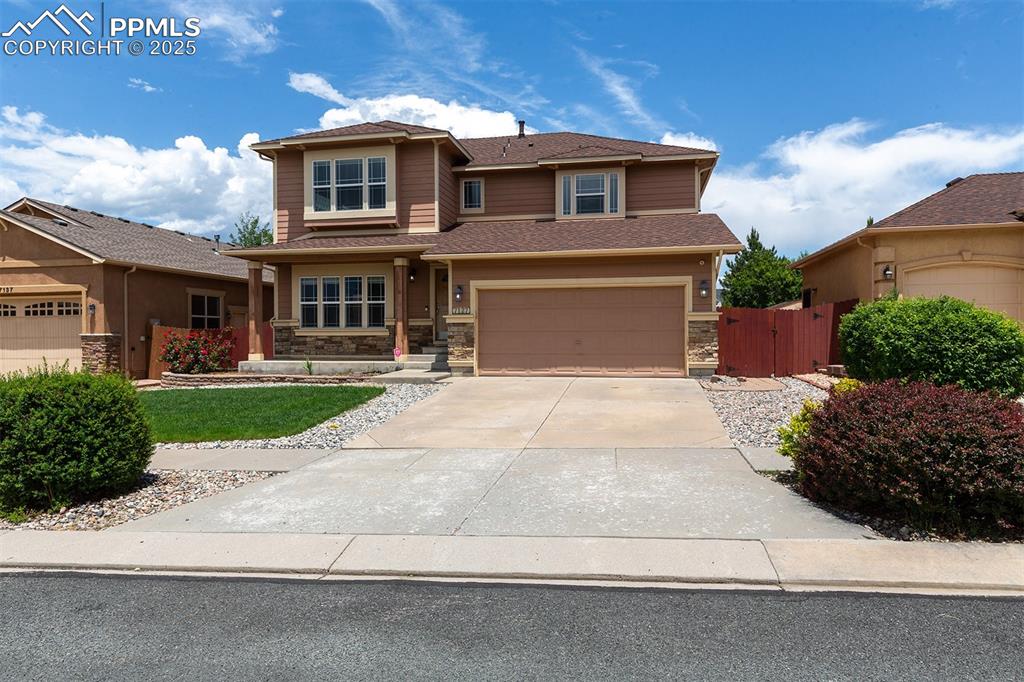 Image 44 of 46: Prairie-style house featuring stone siding, driveway, a garage, and a gate