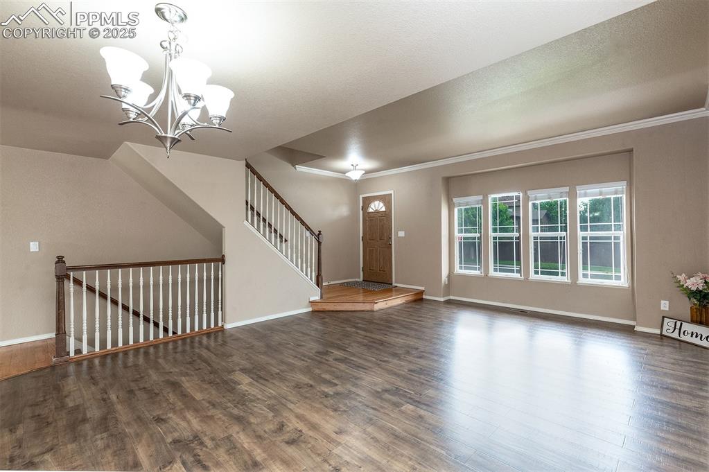 Image 5 of 46: Entrance foyer featuring a chandelier, wood finished floors, and crown mold