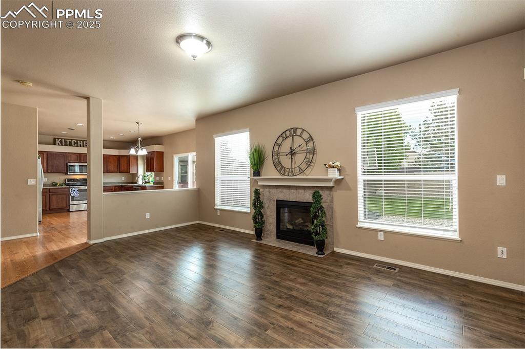 Image 8 of 46: Unfurnished living room featuring a fireplace, dark wood-style flooring, an