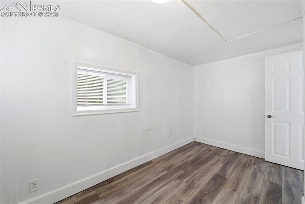 Image 10 of 50: Room featuring wood-finish flooring, white paneling, and a single-pane wind