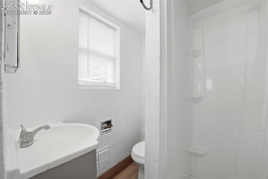 Image 11 of 50: Compact bathroom featuring a white vanity with integrated sink, chrome fauc