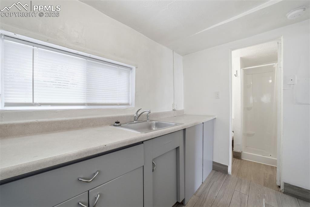 Image 14 of 50: Kitchenette featuring a stainless steel sink with chrome faucet, light grey