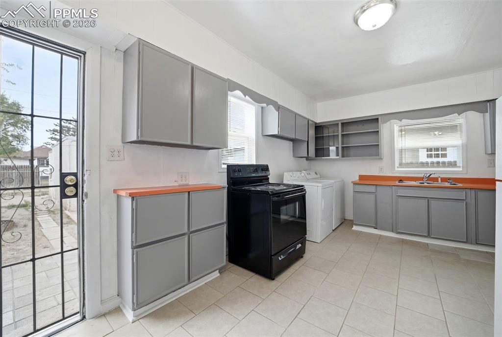 Image 16 of 50: Kitchen featuring gray cabinetry, orange countertops, and a black range