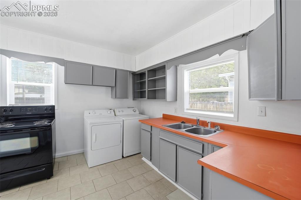 Image 17 of 50: Bright kitchen featuring neutral tile flooring, grey cabinetry, double basi