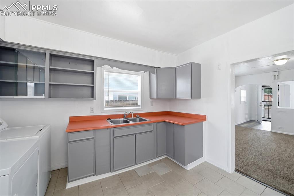Image 19 of 50: Kitchen with gray cabinetry, orange countertops, and a double basin sink