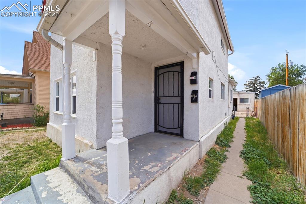 Image 2 of 50: Stucco exterior featuring a covered front porch with decorative columns, a 