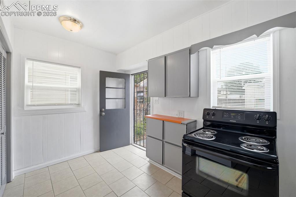 Image 20 of 50: Kitchen featuring tile flooring, white vertical plank wall paneling, a dark