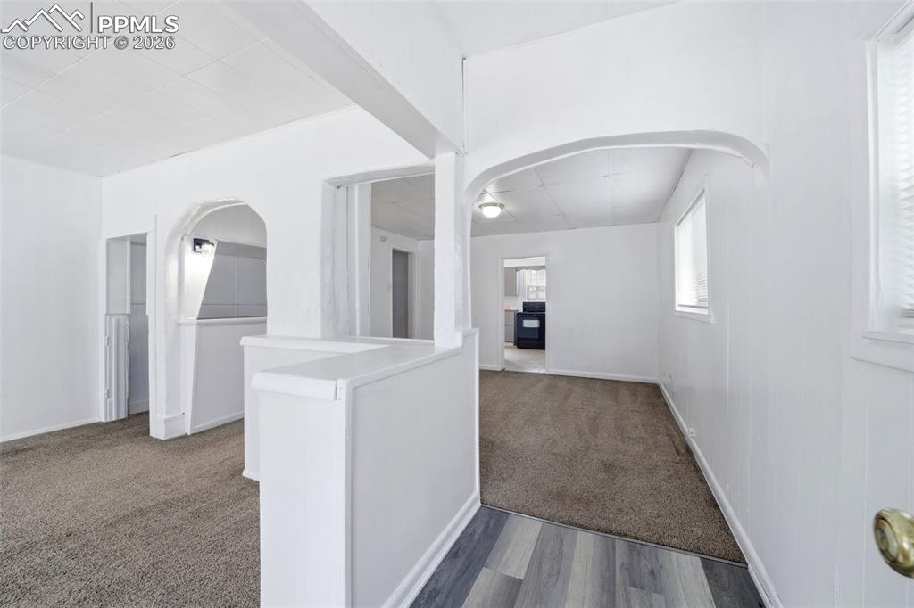 Image 21 of 50: Entryway featuring wood-finish flooring transitioning to carpet, with an ar