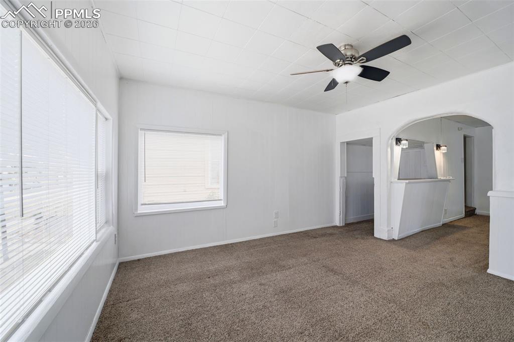 Image 23 of 50: Carpeted living space featuring multiple windows with blinds, a ceiling fan