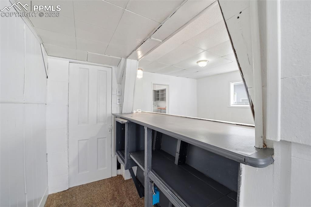 Image 26 of 50: Built-in counter with open shelving, carpet flooring, paneled walls, and a 