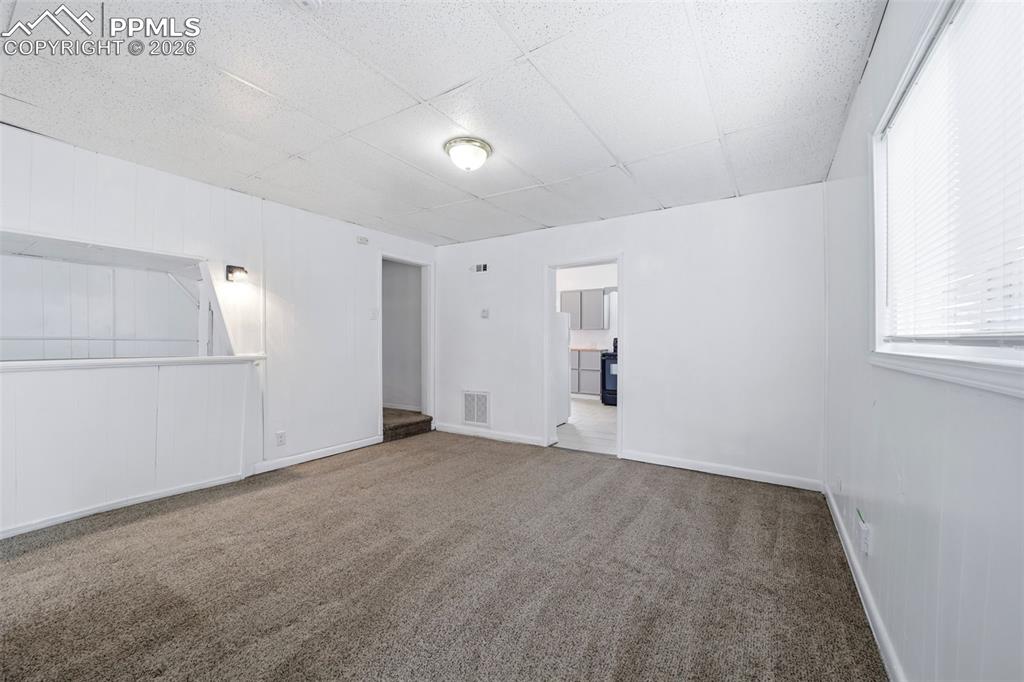 Image 29 of 50: Bright interior space featuring light-colored carpet flooring and white pai