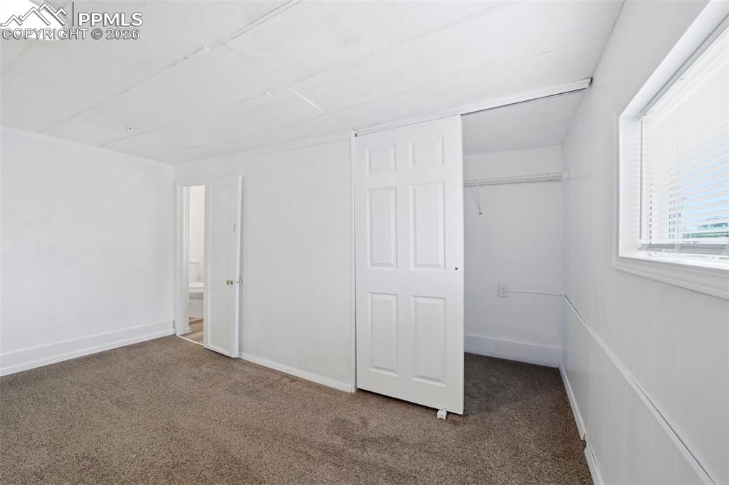 Image 38 of 50: Interior room featuring neutral-toned carpet flooring, white walls, and a w