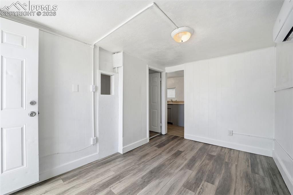 Image 4 of 50: Interior space featuring wood-finish flooring, white paneling, and an expos