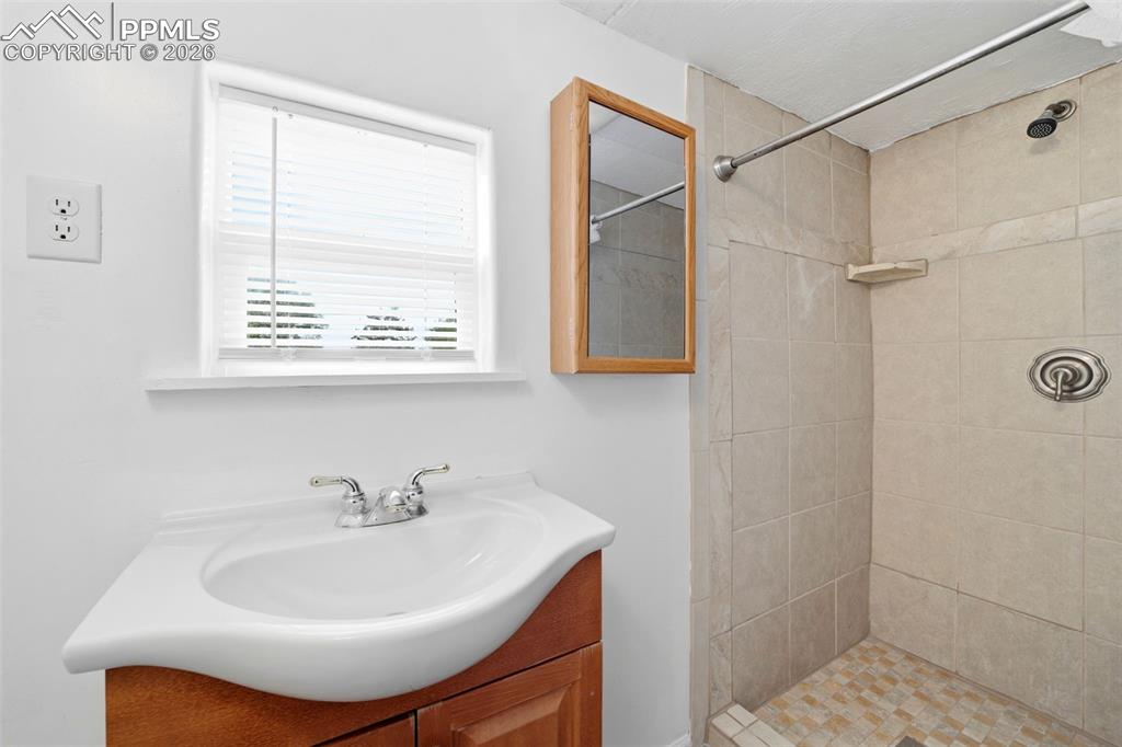 Image 41 of 50: Bathroom featuring a wood-finish vanity with an integrated sink, a mirrored