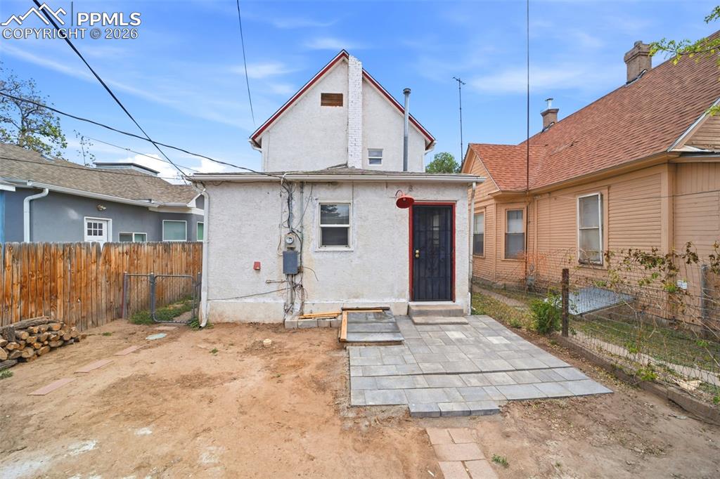 Image 42 of 50: Rear exterior featuring a paver patio and a security screen door