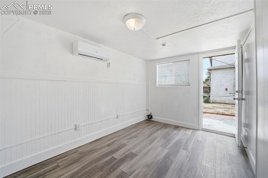Image 6 of 50: Light-filled interior space featuring wood-finish flooring, white beadboard