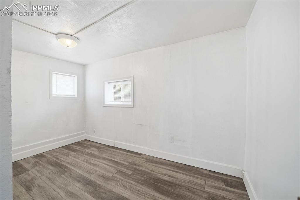 Image 7 of 50: Room with wood-finish flooring, white walls, and white baseboards