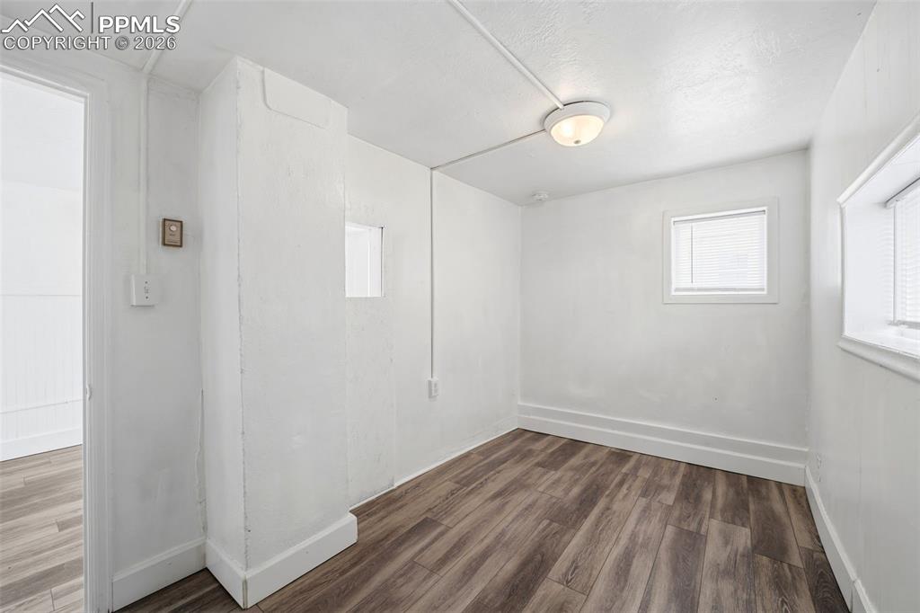 Image 8 of 50: Room featuring wood-finish flooring, white painted walls, and white trim