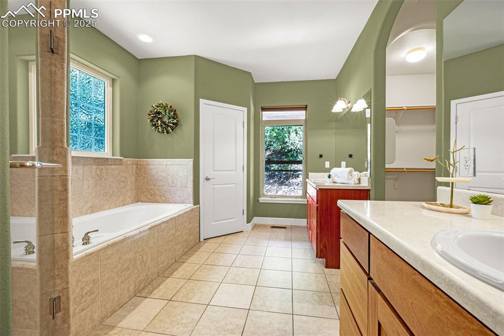 Image 13 of 41: Full bath featuring vanity, a garden tub, tile patterned floors, and a show