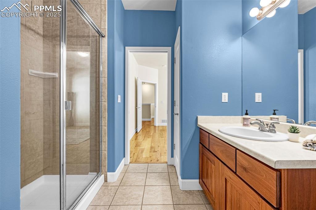 Image 17 of 41: Bathroom with vanity, a stall shower, tile patterned floors, and baseboards