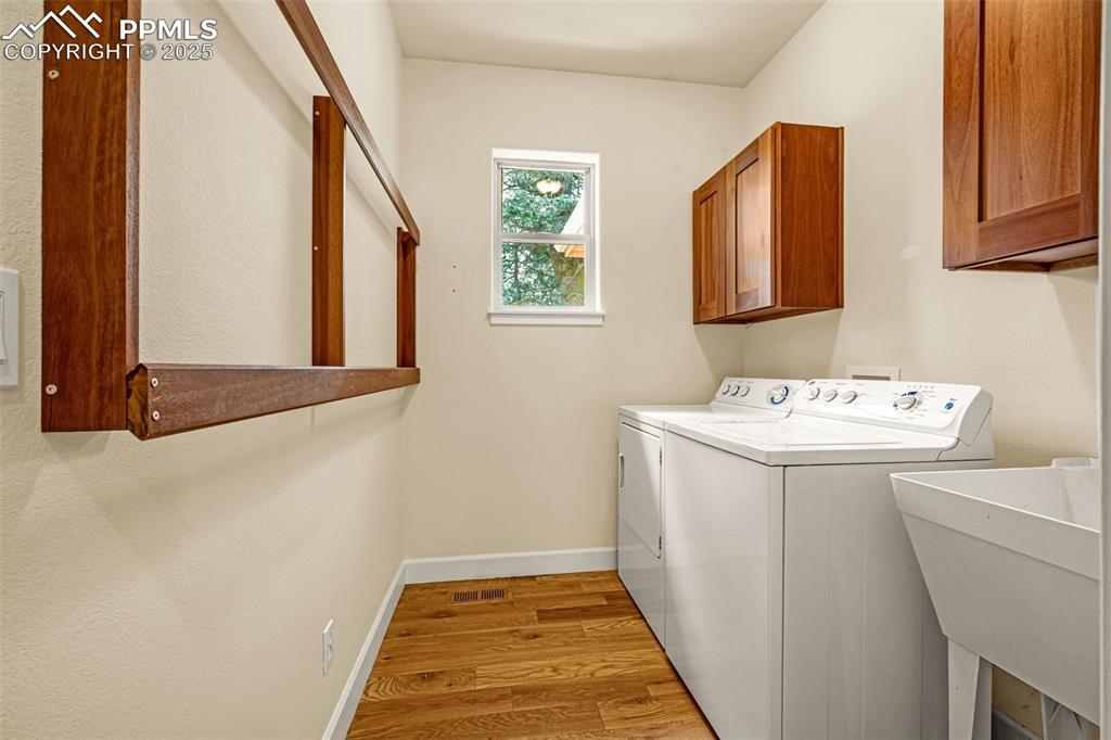 Image 18 of 41: Washroom with washer and dryer, cabinet space, wood finished floors, and ba