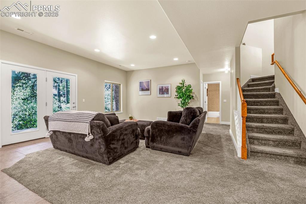 Image 19 of 41: Tiled living room with recessed lighting and stairway
