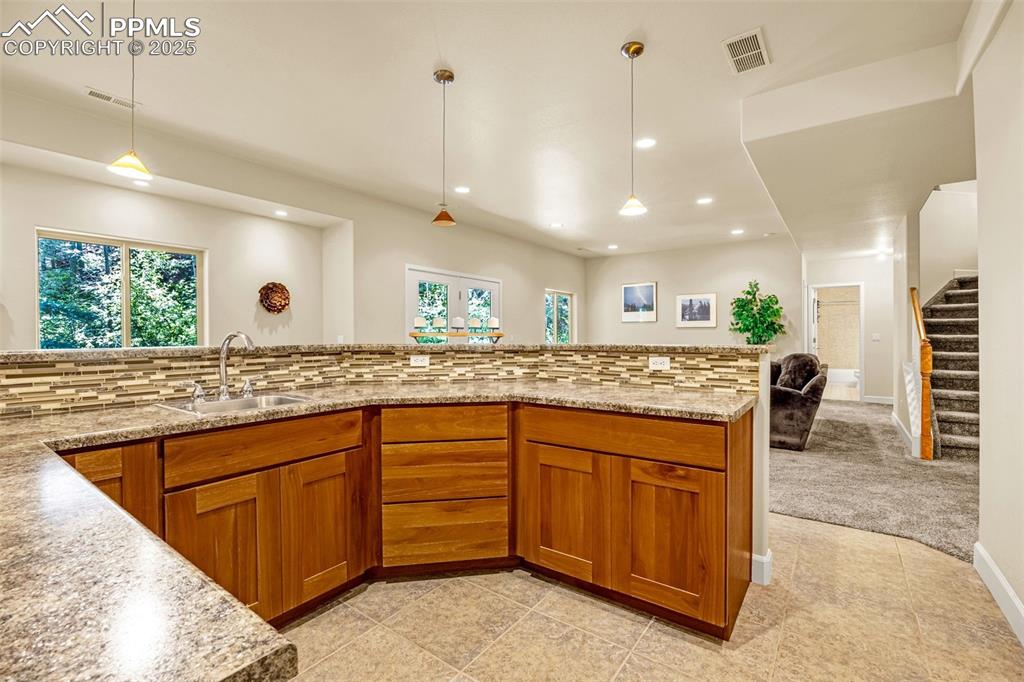 Image 22 of 41: Kitchen with a sink, brown cabinetry, recessed lighting, plenty of natural