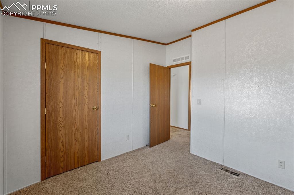 Image 28 of 41: Unfurnished bedroom featuring carpet flooring, crown molding, a textured ce