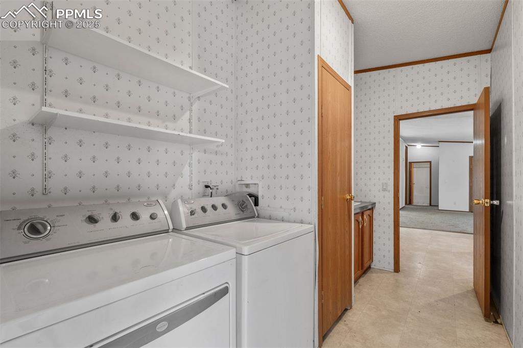 Image 29 of 41: Washroom featuring wallpapered walls, crown molding, separate washer and dr