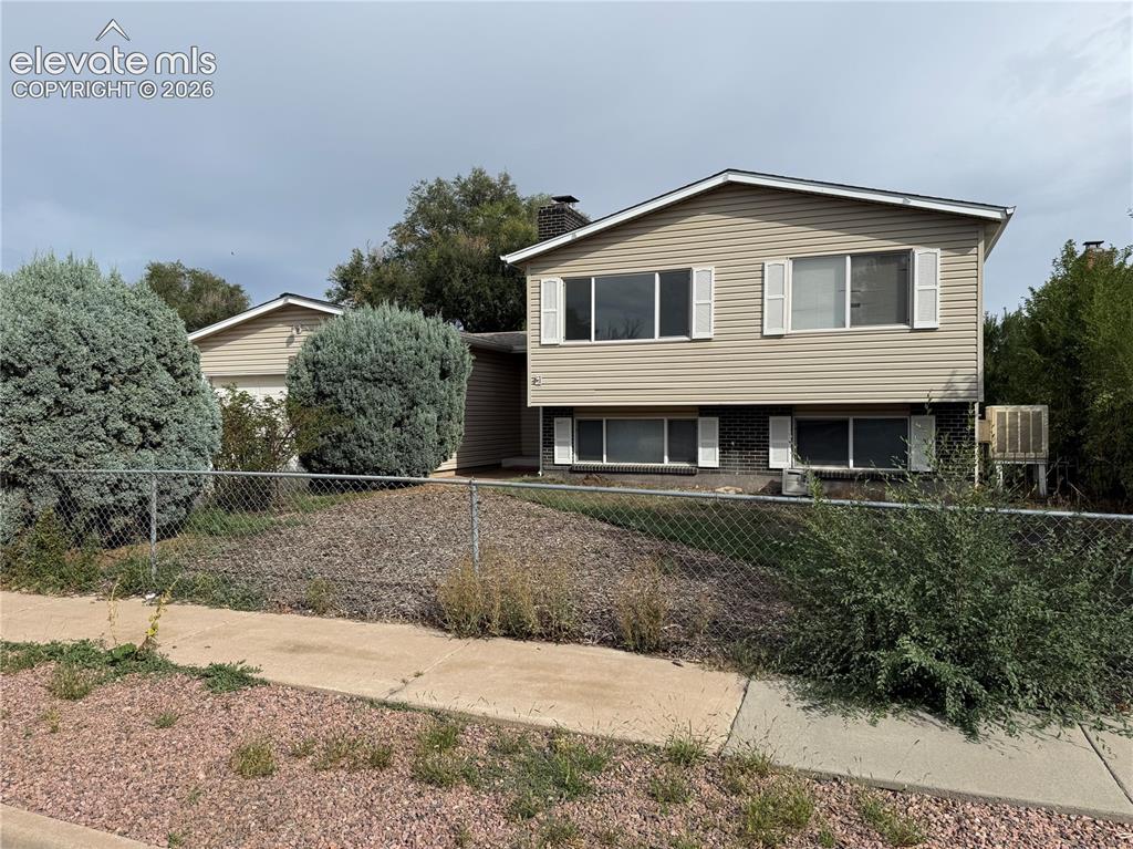 Caption: Split-level home featuring horizontal siding exterior, multiple large windows for natural light, est