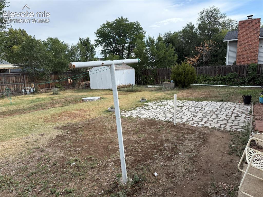 Image 15 of 16: Expansive backyard featuring a patterned paver patio, a freestanding storag