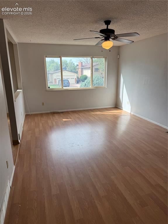 Image 3 of 16: Spacious room featuring wood-finish flooring, a multi-pane window, and a ce