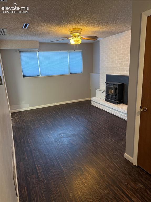 Image 9 of 16: Wood-finish flooring with a brick-clad fireplace, wood-burning stove, ceili