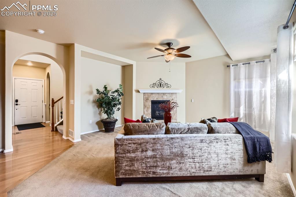 Image 10 of 34: Carpeted living area with a ceiling fan, arched walkways, a glass covered f