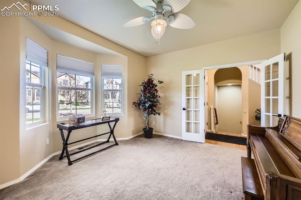 Image 13 of 34: Living area with french doors, carpet, arched walkways, and baseboards
