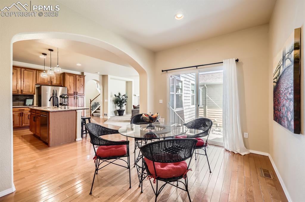 Image 14 of 34: Dining room featuring arched walkways, light wood finished floors, stairway