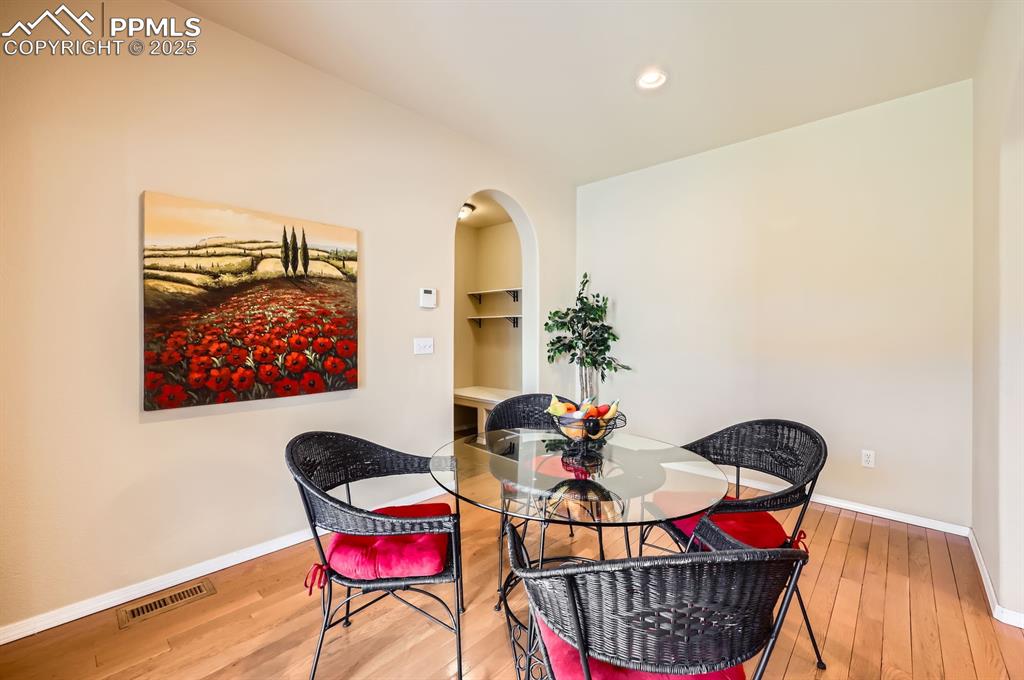Image 15 of 34: Dining space with wood finished floors, baseboards, arched walkways, and re