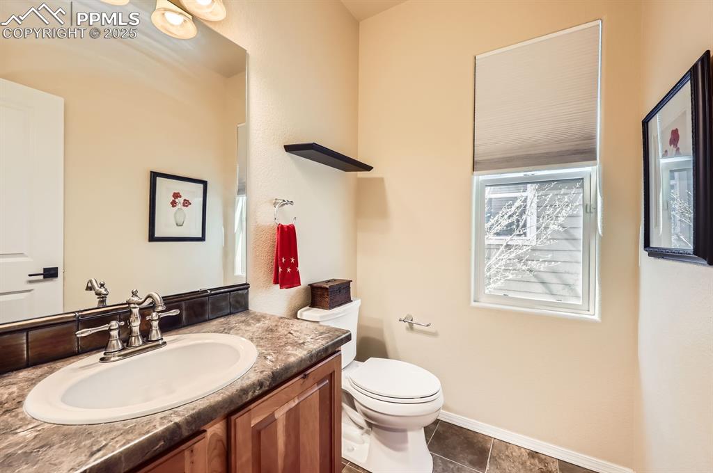 Image 16 of 34: Half bathroom with toilet, vanity, tile patterned flooring, and baseboards