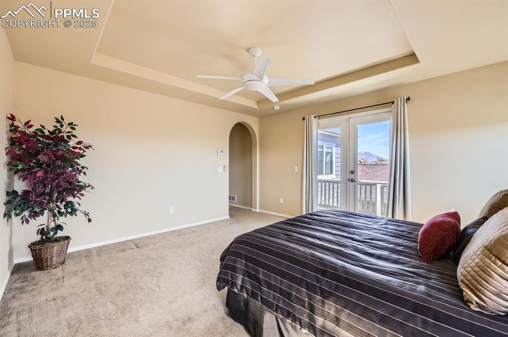 Image 19 of 34: Bedroom featuring a raised ceiling, access to outside, arched walkways, car