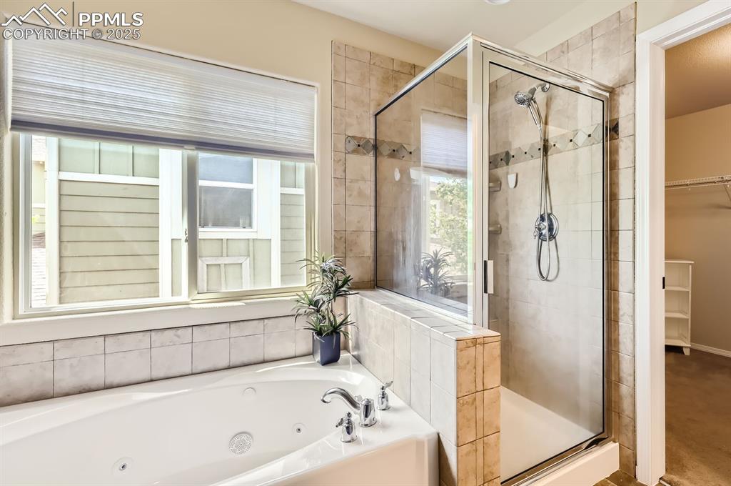 Image 21 of 34: Bathroom featuring a stall shower, a jetted tub, and a walk in closet