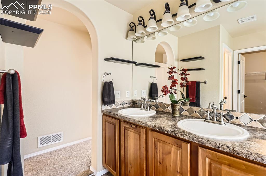 Image 22 of 34: Bathroom with double vanity, baseboards, and a walk in closet