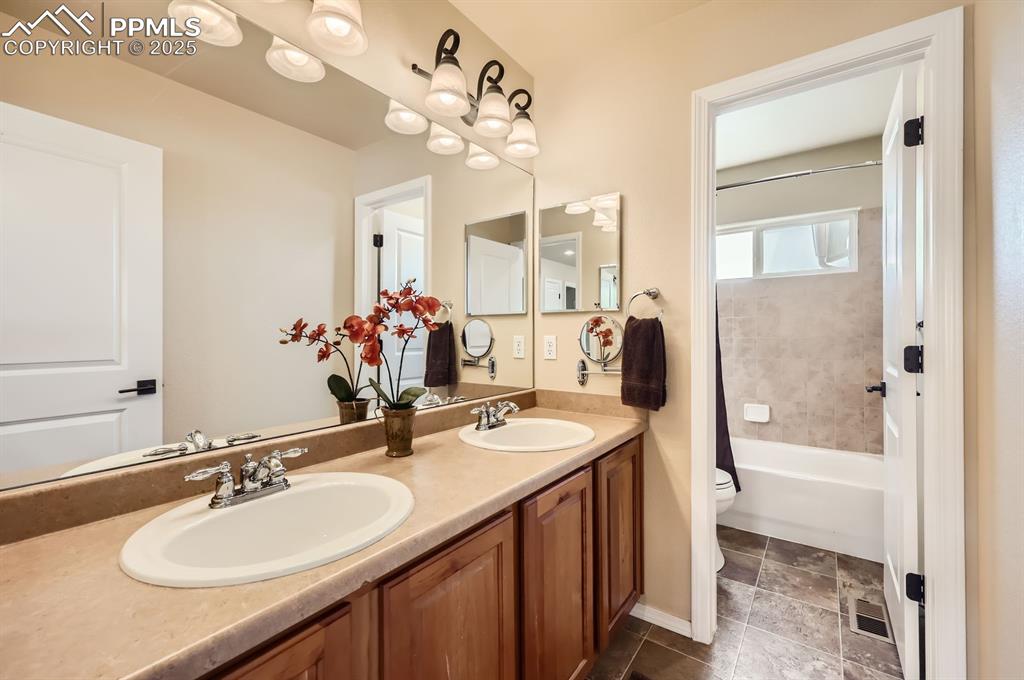 Image 23 of 34: Full bathroom with toilet, double vanity, and washtub / shower combination