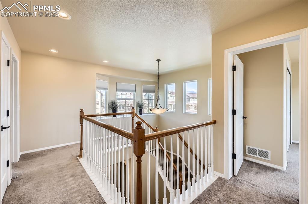 Image 24 of 34: Hall featuring an upstairs landing, carpet, healthy amount of natural light
