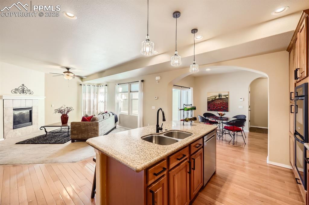 Image 8 of 34: Kitchen with a sink, arched walkways, open floor plan, brown cabinetry, and